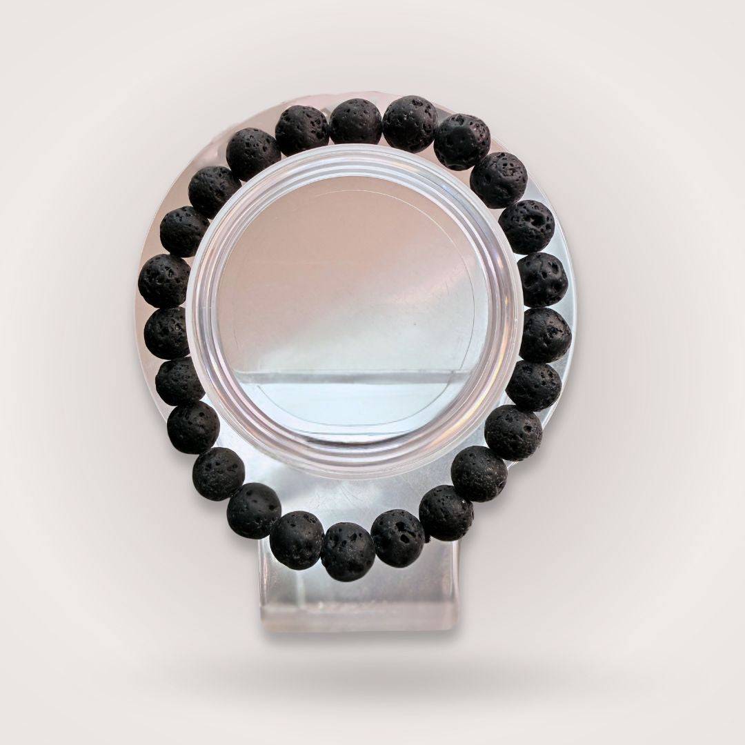 Lava Stone 8mm Beaded Bracelet - Grounding, Strength, & Resilience displayed on a clear stand, showcasing its porous black beads in a circular form.
