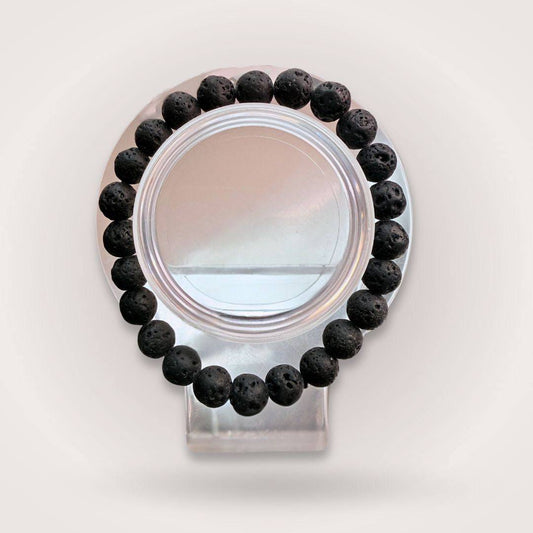 Lava Stone 8mm Beaded Bracelet - Grounding, Strength, & Resilience displayed on a clear stand, showcasing its porous black beads in a circular form.
