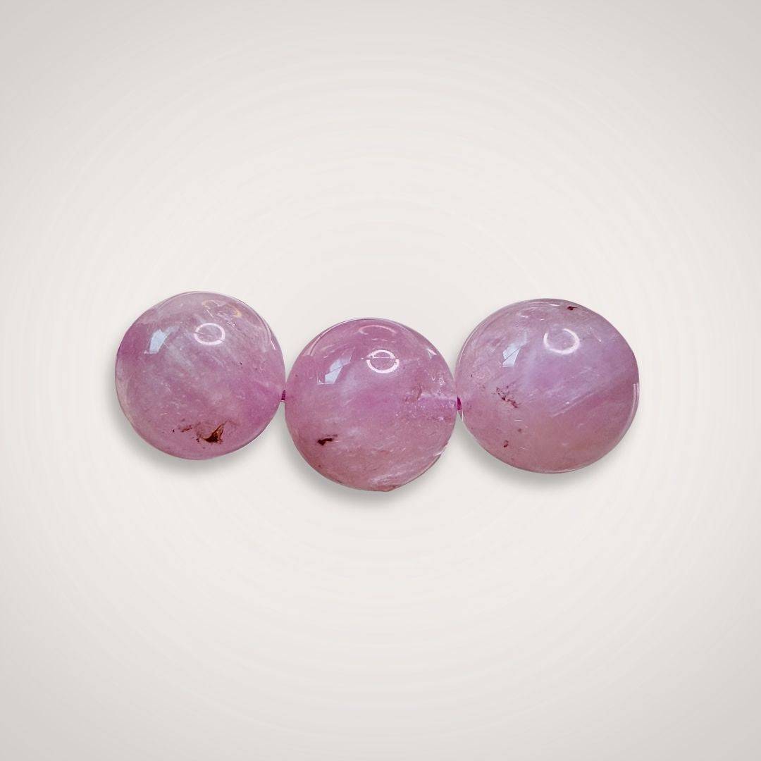 Close-up of three 12mm Lavender Amethyst beads, emphasizing their natural clarity, soft purple color, and polished finish for emotional balance.