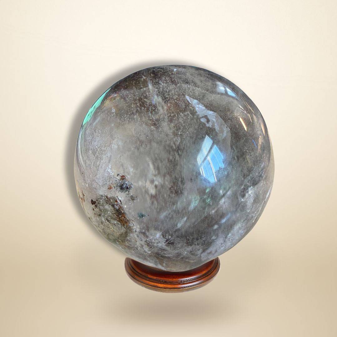 Dark-toned Lodolite Garden Quartz Sphere on stand, showcasing unique inclusions for metaphysical and meditation practices.