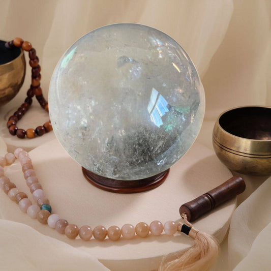 Lodolite Garden Quartz Sphere displayed with mala beads and singing bowls, perfect for dreamwork and inner vision rituals.