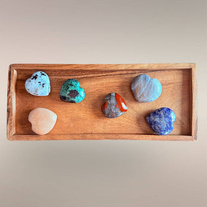 Mixed Madagascar heart stones arranged in a wooden tray, showing assorted colors and polished heart shapes.