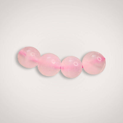 Close-up of four 8mm Mangano Calcite beads in soft pink, highlighting their smooth finish and calming energy for emotional healing.