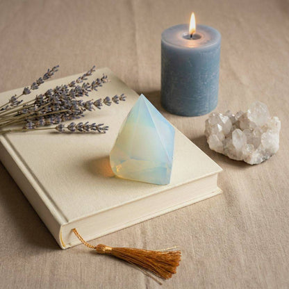 Opalite top polish point tower placed on a book with lavender, candle, and quartz, enhancing calm and balance in home decor settings.