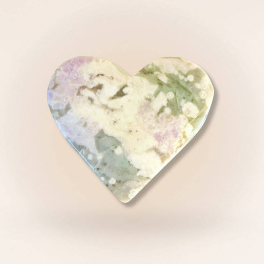 Heart-shaped Peace Jade palm stone with soft lavender, green, and cream hues, carved from serpentine and stichtite for emotional balance.