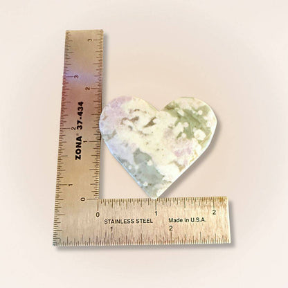 Heart-shaped Peace Jade palm stone measured with a ruler, showing size and detail in lavender serpentine and stichtite carving.