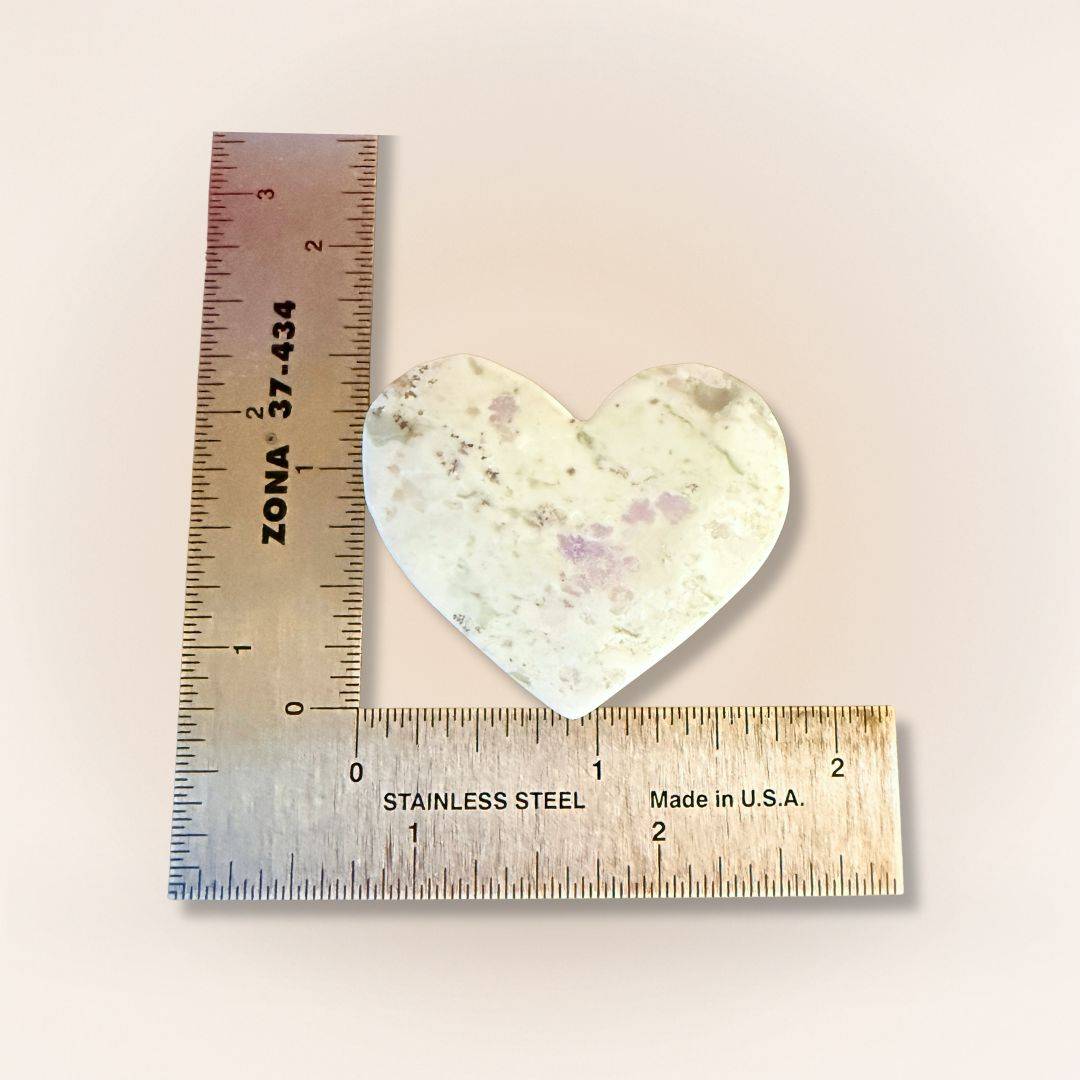 Heart-shaped Peace Jade palm stone next to ruler, featuring lavender serpentine and stichtite for emotional clarity and calm.