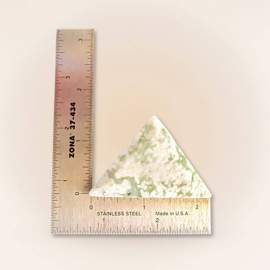 Peace Jade palm stone in a triangle shape, featuring lavender serpentine and stichtite with quartz. Shown next to a ruler for size reference.