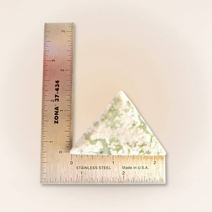 Peace Jade palm stone in a triangle shape, featuring lavender serpentine and stichtite with quartz. Shown next to a ruler for size reference.