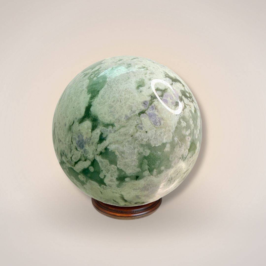 Peace Jade Sphere 66mm with green and white marbling on wooden stand, ideal for heart-calming energy and inner peace rituals.