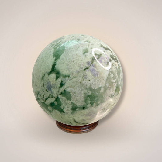 Peace Jade Sphere 66mm with green and white marbling on wooden stand, ideal for heart-calming energy and inner peace rituals.
