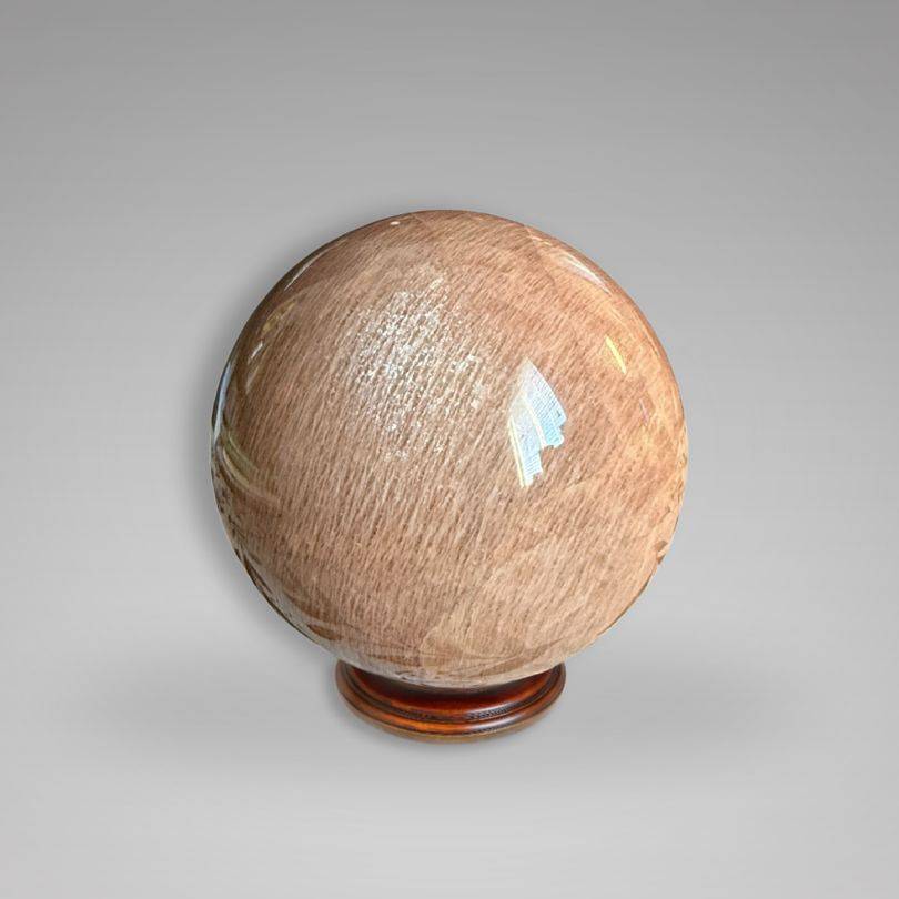 Flashy Peach Moonstone Sphere — Nurturing & Balancing gemstone with shimmering surface on wooden stand, ideal for crystal collectors.
