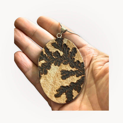 Hand holding large Psilomelane Jasper pendant with striking dendritic patterns. Unique grounding stone for spiritual jewelry collections.