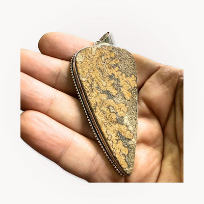 Psilomelane Jasper Pendant | Grounding, Protection, Self-awareness. Pendant held in hand to display its size, texture, and handcrafted silver bezel setting.
