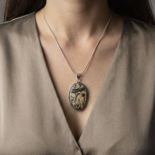 Psilomelane Jasper Pendant worn on model, showcasing its grounding energy and bold natural design. A unique accessory for resilience and style.