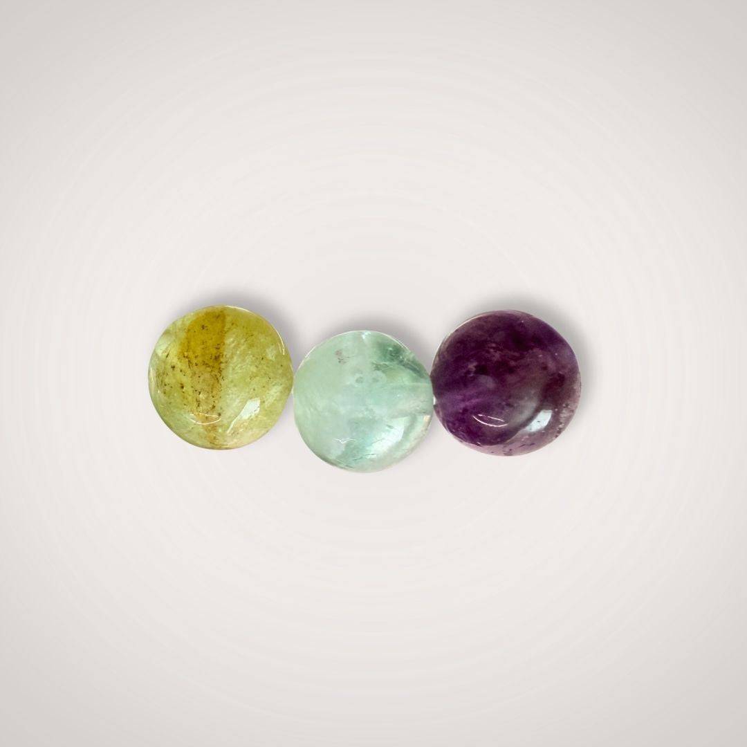Close-up of three polished Rainbow Fluorite beads in yellow, green, and purple hues, highlighting the natural beauty and clarity-enhancing properties.