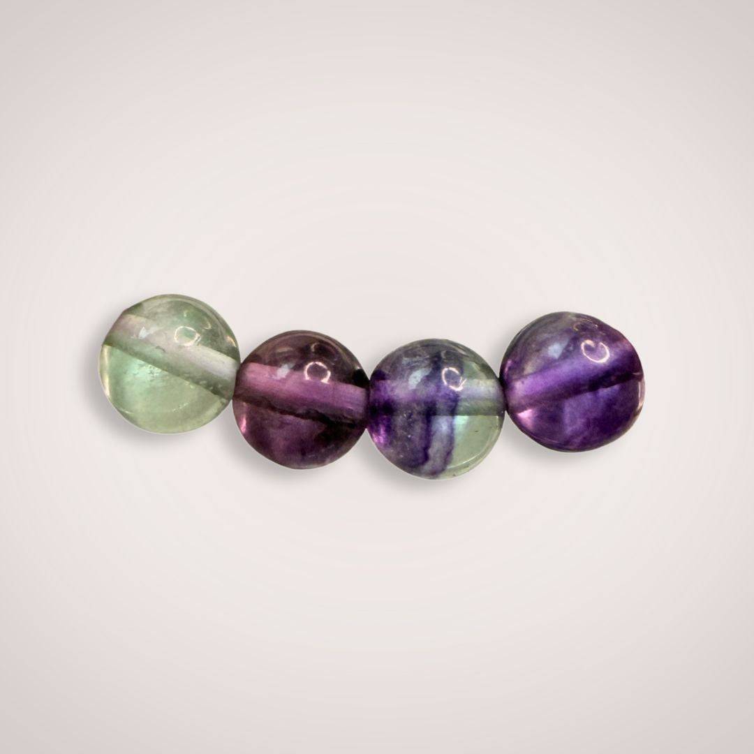 Close-up of four 8mm Rainbow Fluorite beads showing green, purple, and clear hues, ideal for clarity and emotional harmony.