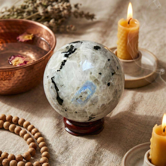 Rainbow Moonstone Sphere 50mm used in a calming ritual setup with candles and beads, perfect for meditation and new beginnings.