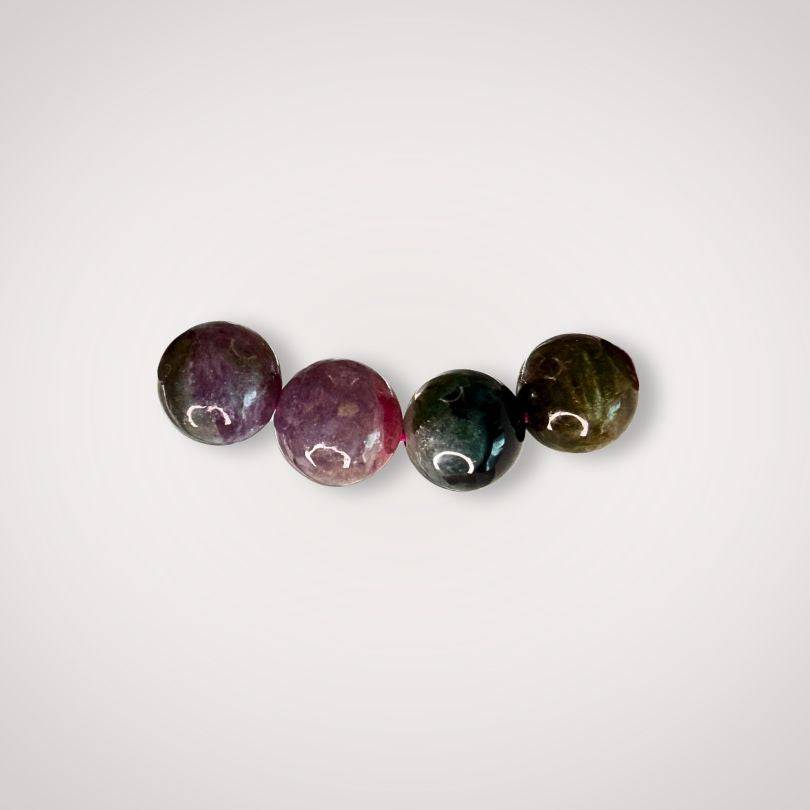 Close-up of four 9mm Rainbow Tourmaline beads in varying shades, emphasizing the natural color variation and quality of the emotional balance bracelet.