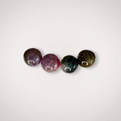 Close-up of four 9mm Rainbow Tourmaline beads in varying shades, emphasizing the natural color variation and quality of the emotional balance bracelet.