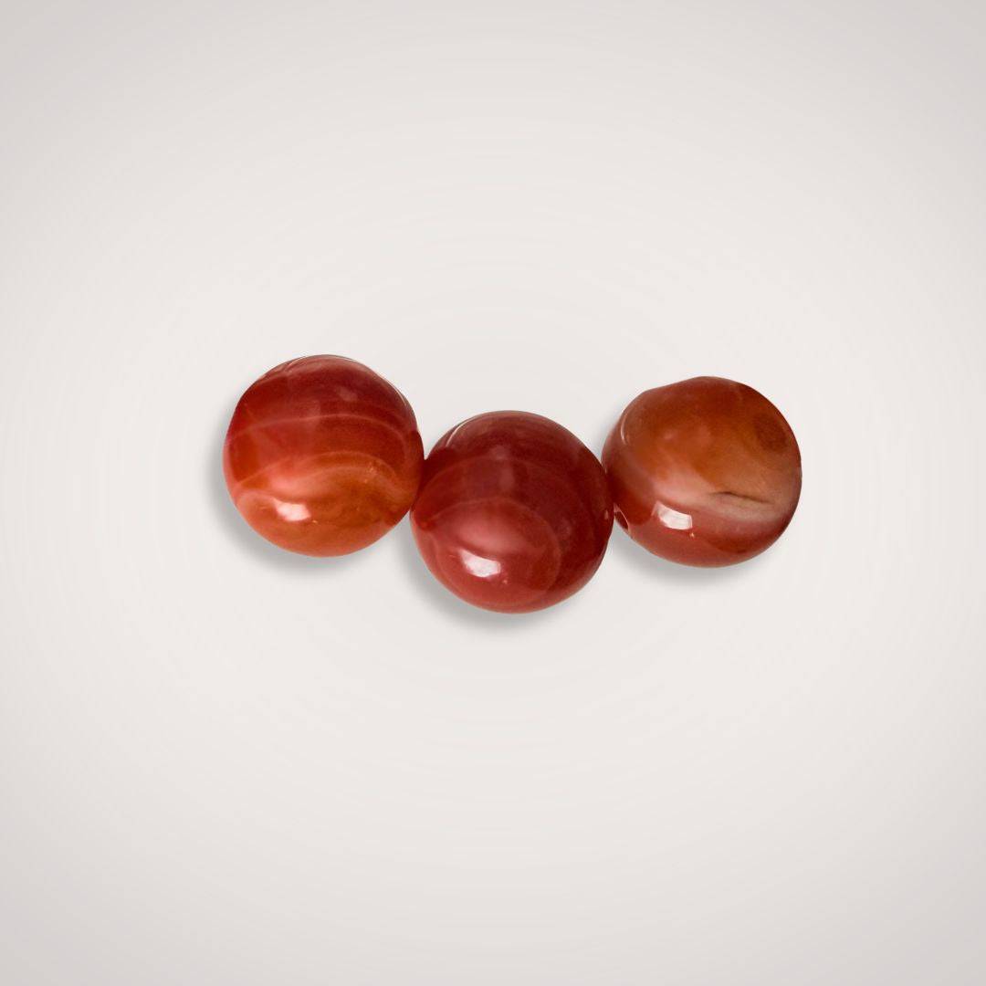 Close-up of three 12mm Red Botswana Agate beads showcasing natural banding and rich red tones, ideal for handcrafted stability bracelets.