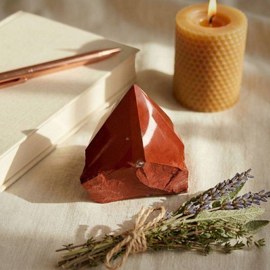 Red Jasper grounding tower displayed with candle, herbs, and journal, perfect for meditation and daily rituals in spiritual gemstone setups.