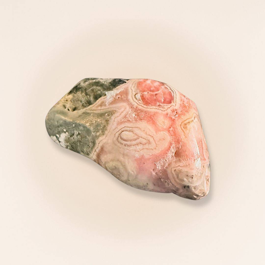 Close-up of Rhodochrosite stone with pink, white, and gray patterns, handheld for jewelry or healing