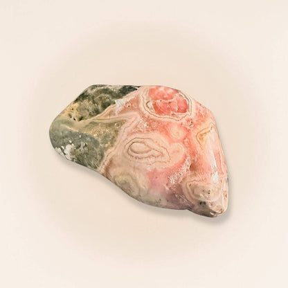 Close-up of Rhodochrosite stone with pink, white, and gray patterns, handheld for jewelry or healing