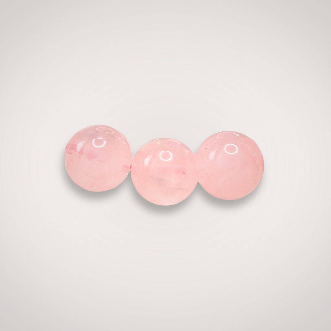 Close-up of three 8mm Rose Quartz beads, emphasizing their smooth finish and gentle pink tone ideal for emotional healing jewelry.