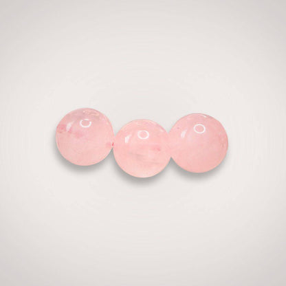 Close-up of three 8mm Rose Quartz beads, emphasizing their smooth finish and gentle pink tone ideal for emotional healing jewelry.