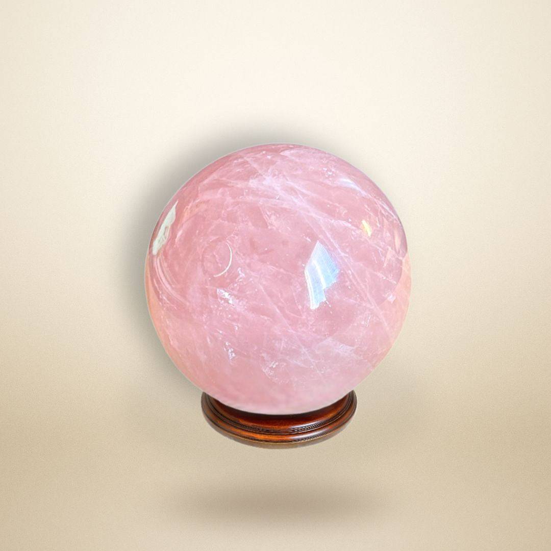 Rose Quartz Sphere 350–400g from Madagascar displayed on a wooden stand, showcasing its soft pink hue and polished surface for heart healing.