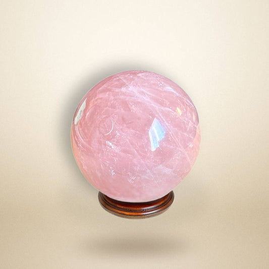 Rose Quartz Sphere 350–400g from Madagascar displayed on a wooden stand, showcasing its soft pink hue and polished surface for heart healing.