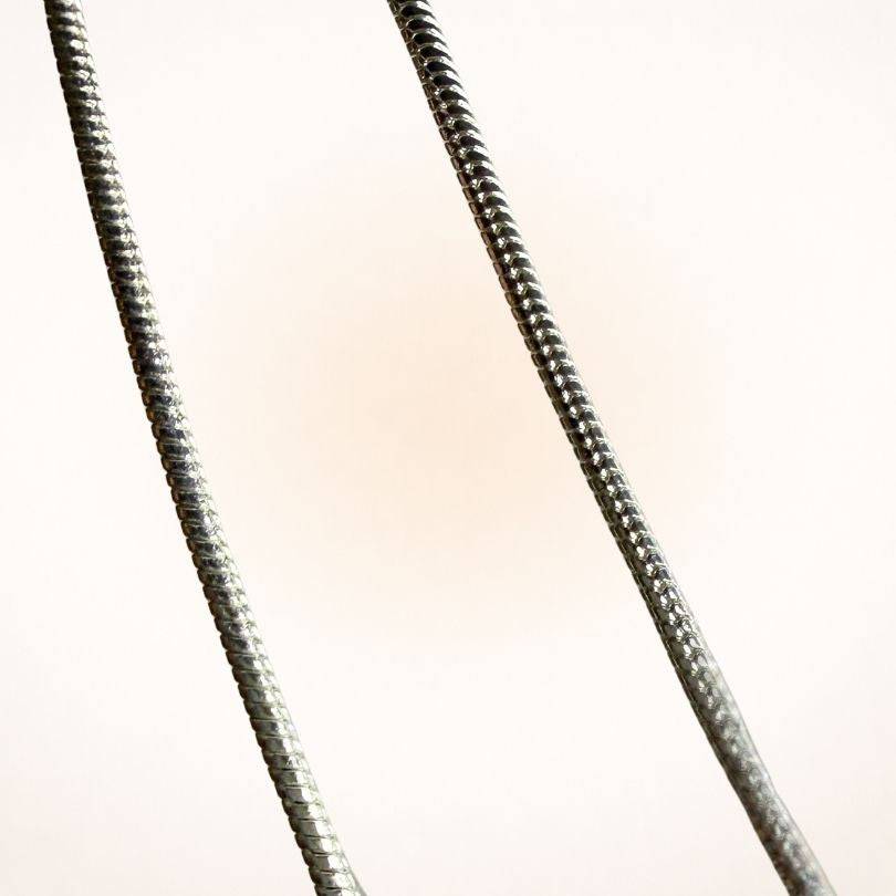 Close-up of the Silver Snake Chain Necklace texture. Features a smooth, flexible design ideal for everyday wear and pendant pairing.