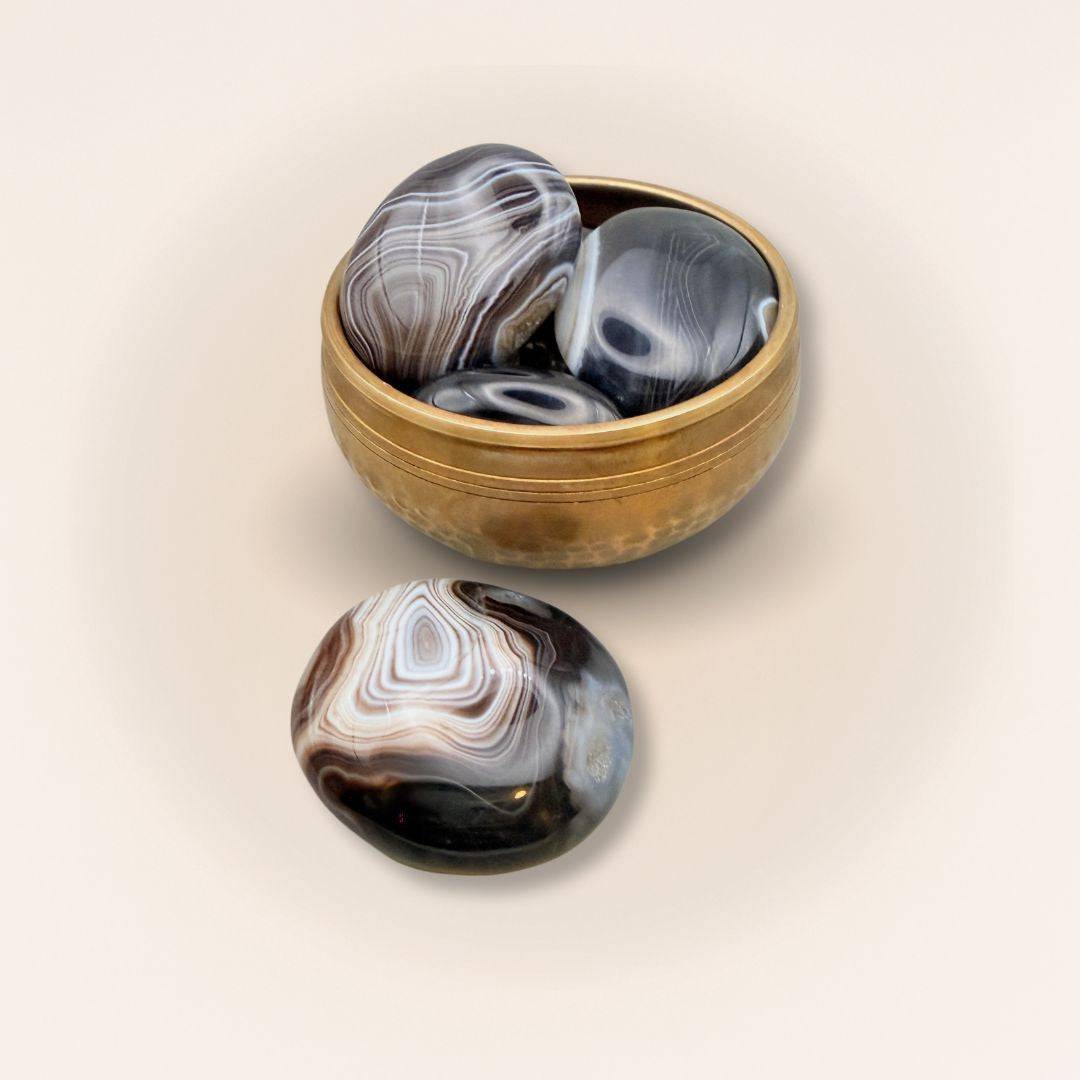 Collection of medium Sardonyx palm stones in a brass bowl, showcasing polished finishes and natural earthy patterns for crystal healing.