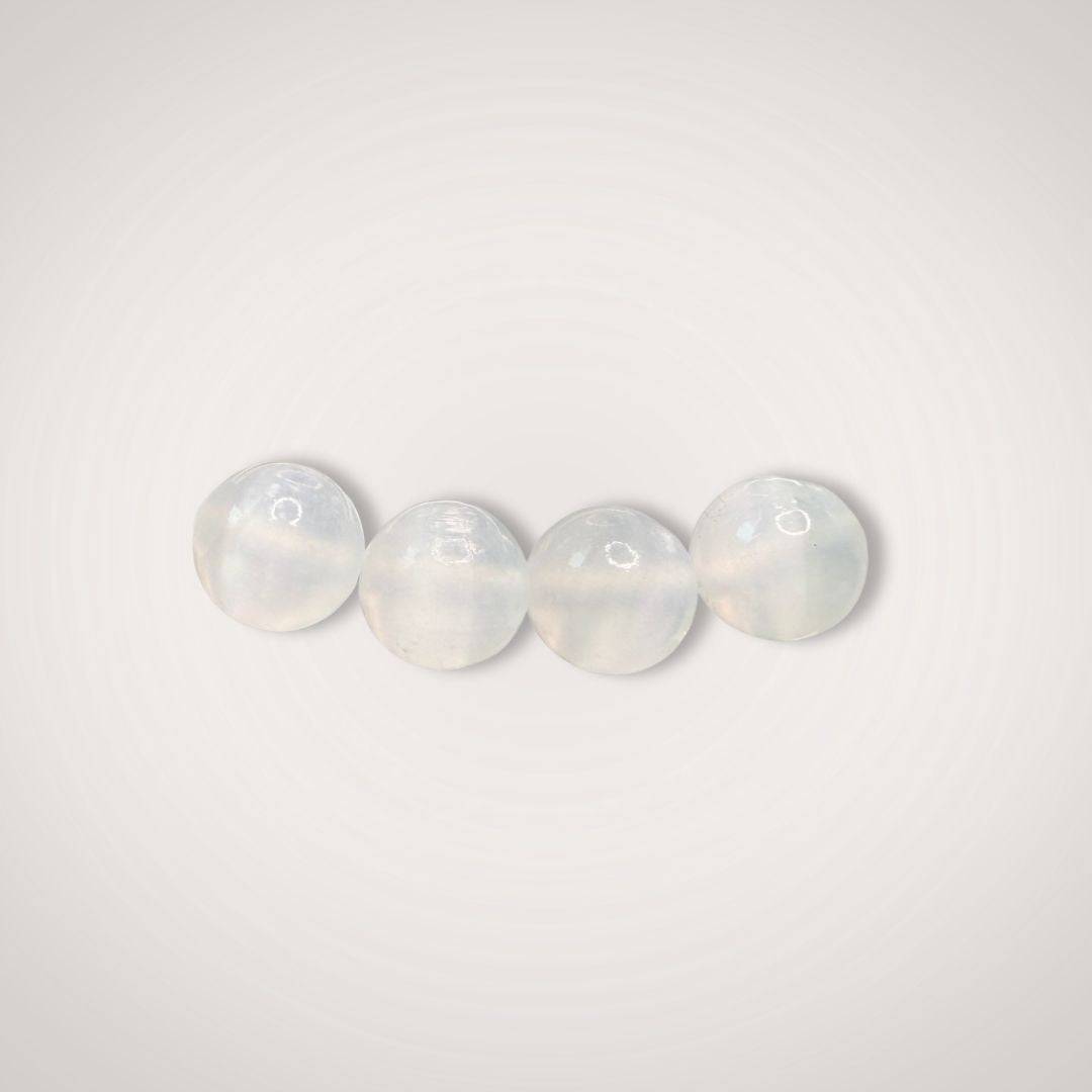 Close-up of four 8mm selenite beads from the Selenite Beaded Bracelet, emphasizing their smooth, polished finish and luminous white tone.