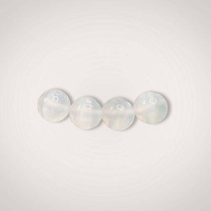 Close-up of four 8mm selenite beads from the Selenite Beaded Bracelet, emphasizing their smooth, polished finish and luminous white tone.