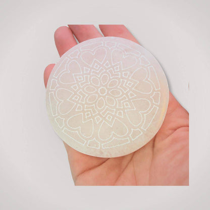 Handheld Selenite Charging Plate featuring intricate mandala engraving, used for spiritual alignment and recharging ritual tools or crystals.