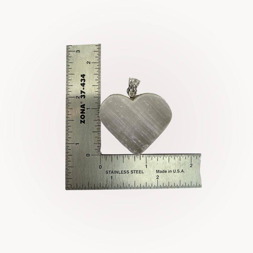 Selenite Raw Front Heart Pendant shown with ruler for scale, emphasizing its size and handcrafted detail for energy healing jewelry.