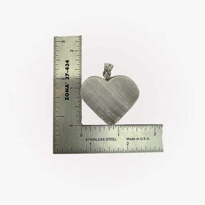 Selenite Raw Front Heart Pendant shown with ruler for scale, emphasizing its size and handcrafted detail for energy healing jewelry.