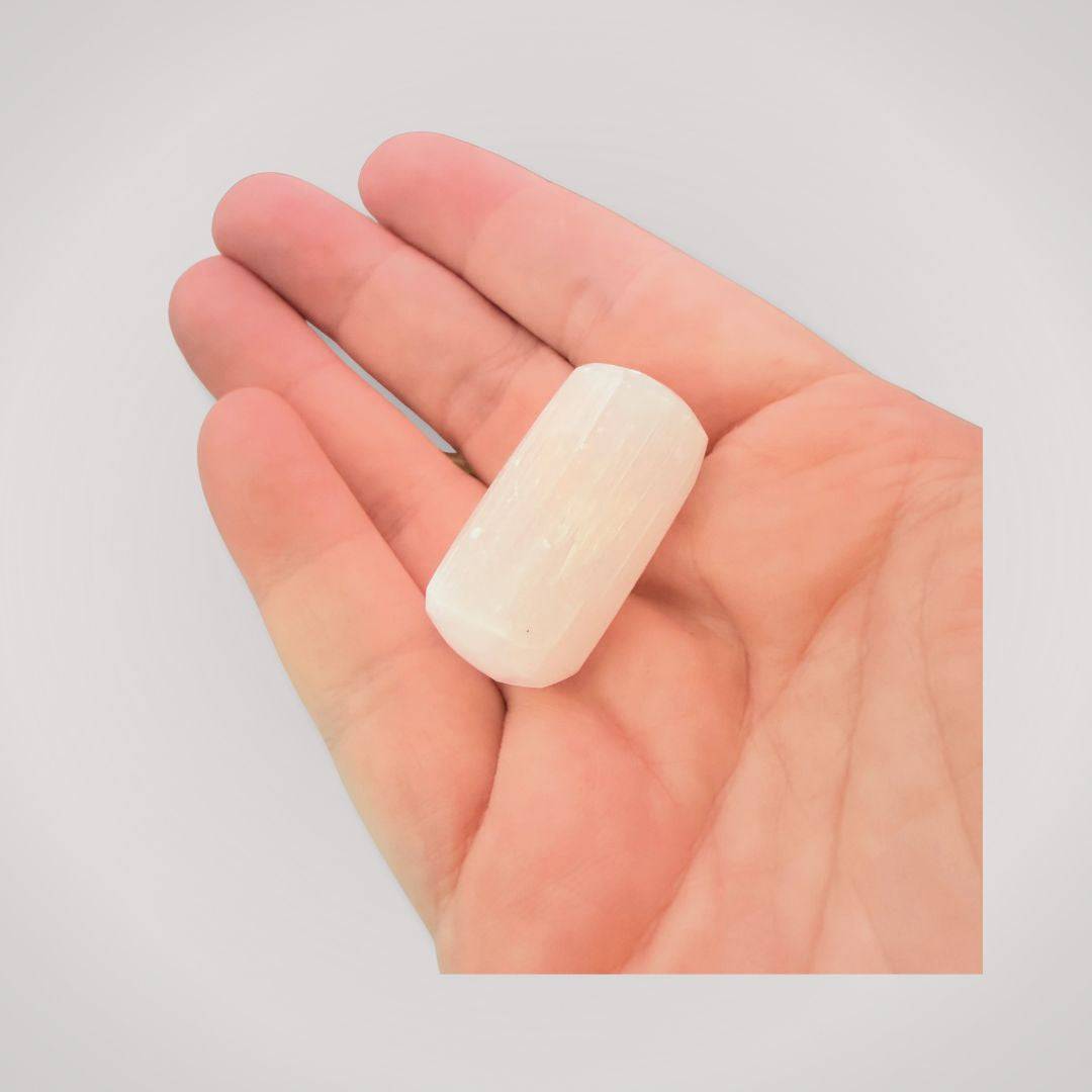 Hand holding a polished Selenite tumbled stone, highlighting its size and luminous finish for daily healing use.