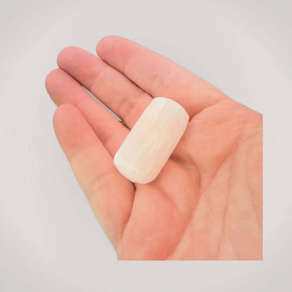 Hand holding a polished Selenite tumbled stone, highlighting its size and luminous finish for daily healing use.