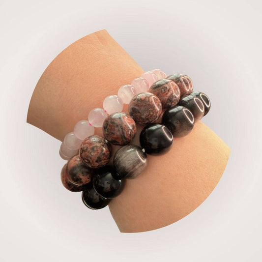 Stacked beaded bracelets on wrist featuring Silver Obsidian 12mm Bracelet for protection and clarity, paired with rose quartz and jasper designs.