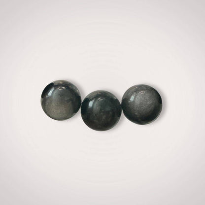 Close-up of three 12mm Silver Obsidian beads highlighting their smooth finish and metallic luster, ideal for grounding and shadow work jewelry.