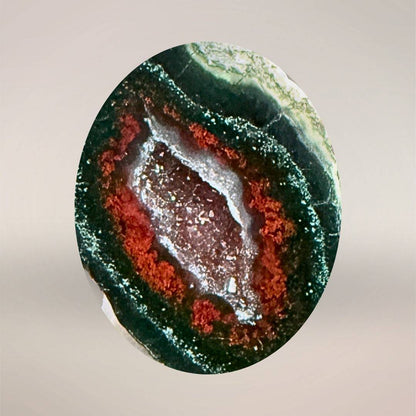 Close up view of Tabasco Agate micro-geode specimen with vibrant red and green mineral layers and quartz druzy center