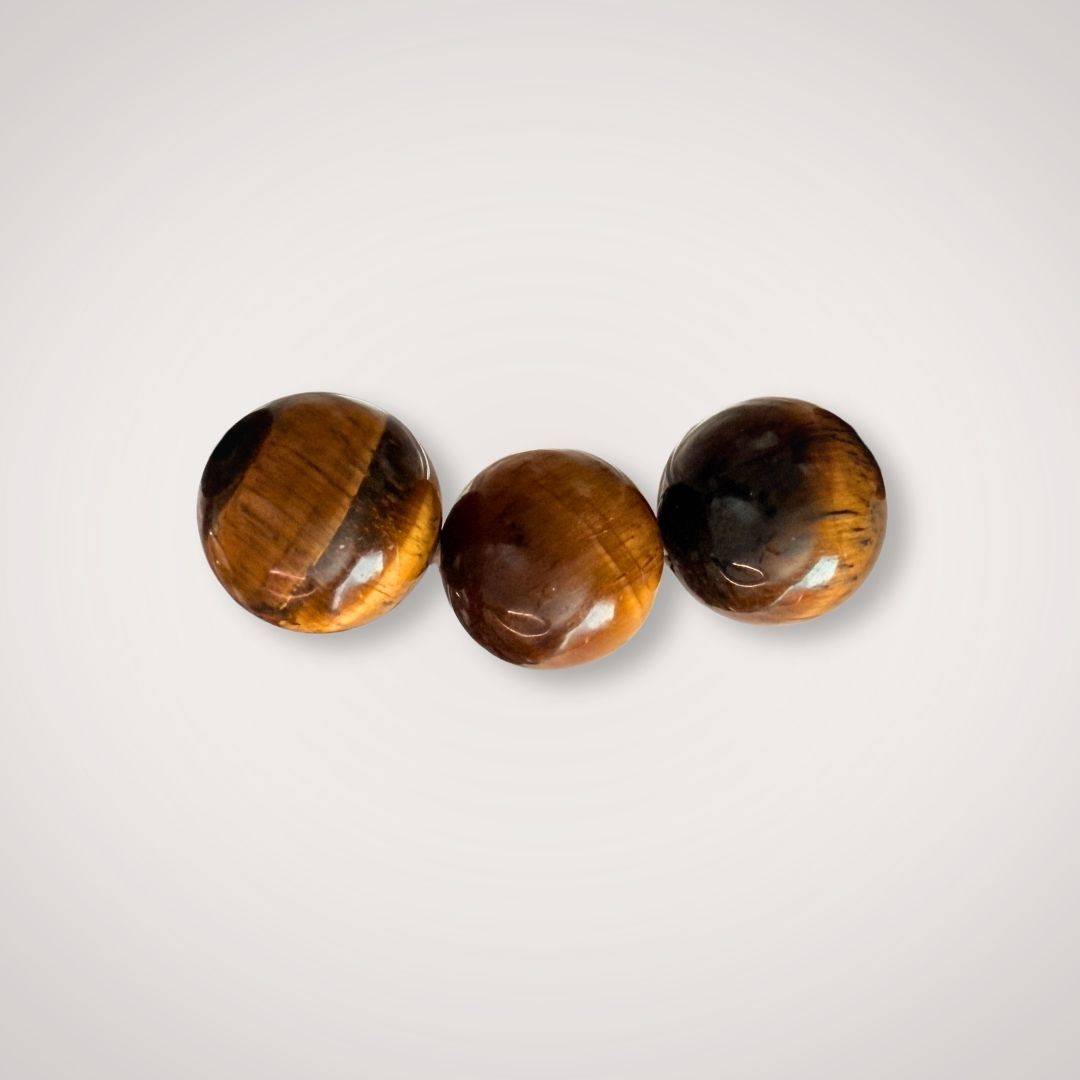 Close-up of three polished 12mm Tiger's Eye beads, emphasizing their natural golden-brown chatoyancy and protective energy properties.