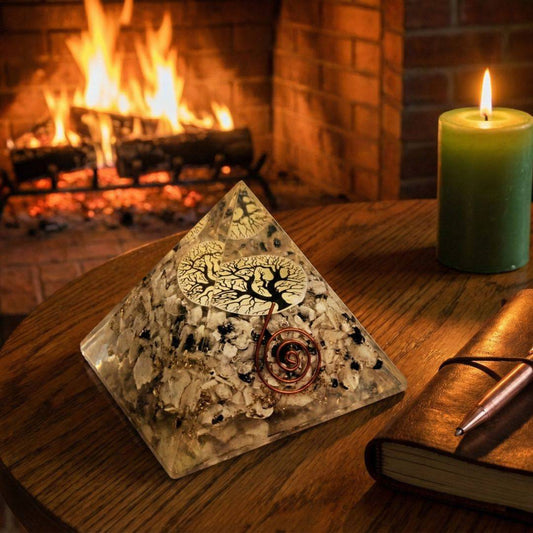 Tourmalinated Quartz Orgonite Pyramid with Tree of Life design placed on a wooden table near a fireplace, ideal for spiritual ambiance and decor.