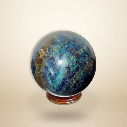 Trinity Stone Sphere 267g with deep blue, green, and golden hues on a wooden stand, ideal for emotional balance and intuitive alignment.