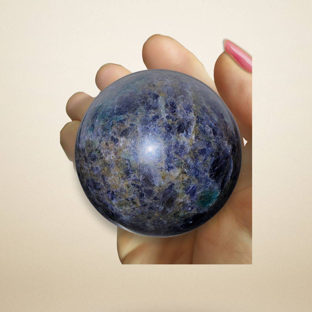 Hand holding the Trinity Stone Sphere 348g, highlighting its polished surface and vibrant mix of Fuchsite, Kyanite, and Garnet minerals.