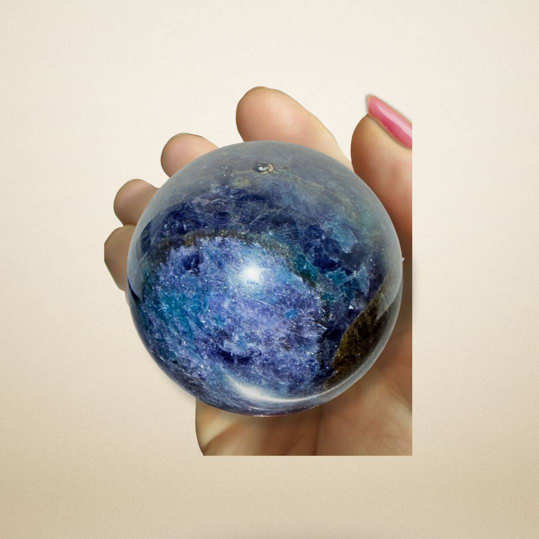 Hand holding the 267g Trinity Stone Sphere, showcasing its compact size and vibrant Fuchsite–Kyanite–Garnet blend for insight and balance.