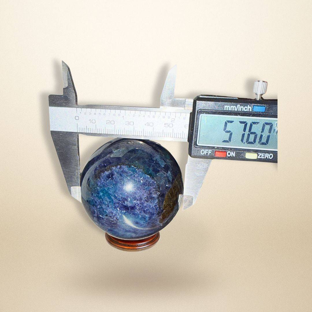 Digital caliper measuring the Trinity Stone Sphere at 57.60mm, confirming its exact size for gemstone collectors and energy practitioners.